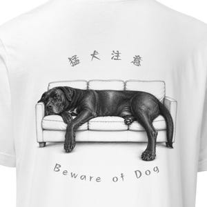 May include: White t-shirt featuring a black and white illustration of a dog lying on a couch. The text "Beware of Dog" is below the image, with Japanese characters above the dog.