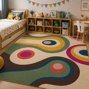 May include: A colorful area rug with a retro design in a child's bedroom. The rug features large, abstract shapes in shades of green, brown, yellow, pink, and blue on a cream background. The room also includes a bed, desk, and storage shelves.