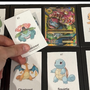 May include: A collection of Pok&eacute;mon trading cards in a binder. One card is being held up, featuring a drawing of Venusaur with the text "#3" and "Venusaur Generation 1". Other cards show Charizard and Squirtle.