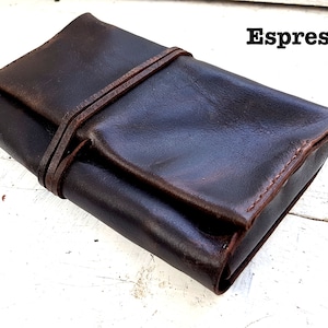 Puede incluir: Un estuche enrollable de cuero marr&oacute;n oscuro con cierre de correa. El estuche est&aacute; hecho de cuero envejecido y tiene un aspecto r&uacute;stico. El texto "Espresso" es visible en la esquina superior derecha de la imagen.