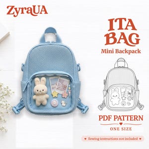 May include: A light blue mini ita bag backpack with a clear front pocket displaying a plush bunny, two polaroid-style photos, a star pin, a flower pin, a circular cat pin, and a small cat charm. Text reads ZyraUA ITA BAG Mini Backpack.