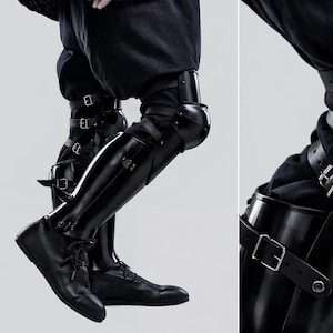 May include: Black leather leg armor with multiple straps and buckles, paired with black shoes. The armor covers the legs from the knees down, with a glossy finish. The image is set against a plain background.