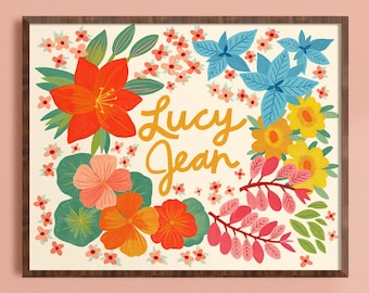 May include: A rectangular wall art print in a dark wood frame featuring the name Lucy Jean in yellow cursive script, surrounded by a vibrant floral illustration with red, orange, pink, yellow, and blue flowers and green leaves on a cream background.