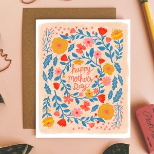 May include: A card with a floral design in shades of pink, yellow, blue, and red. The card has the text 'happy mother's day' in a blue cursive font.