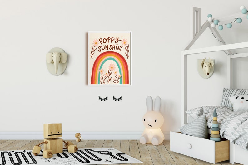 May include: A framed art print with the words "Poppy Sunshine" above a rainbow and flowers. The room features a wooden toy, a bunny lamp, and decorative animal heads on the wall, creating a playful nursery theme.