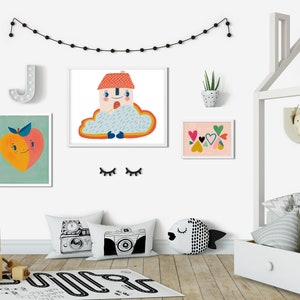 May include: A white wooden bed frame with a house-shaped headboard, a white and gray striped duvet cover, and a white and gray patterned throw pillow. There are several colorful framed prints on the wall behind the bed, including a peach, a house in a cloud, and a collection of hearts.