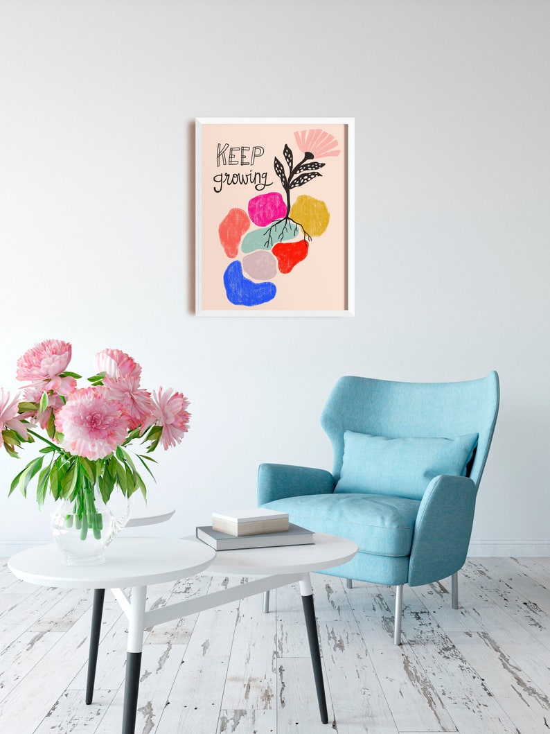 May include: A framed print with a pink background and a black and white illustration of a plant with colorful abstract shapes around it. The text "KEEP GROWING" is written in black cursive.