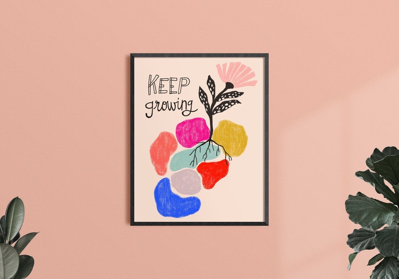 May include: A framed print with a colorful abstract design of a flower growing from a cluster of colorful shapes. The text "KEEP growing" is written in black cursive lettering.