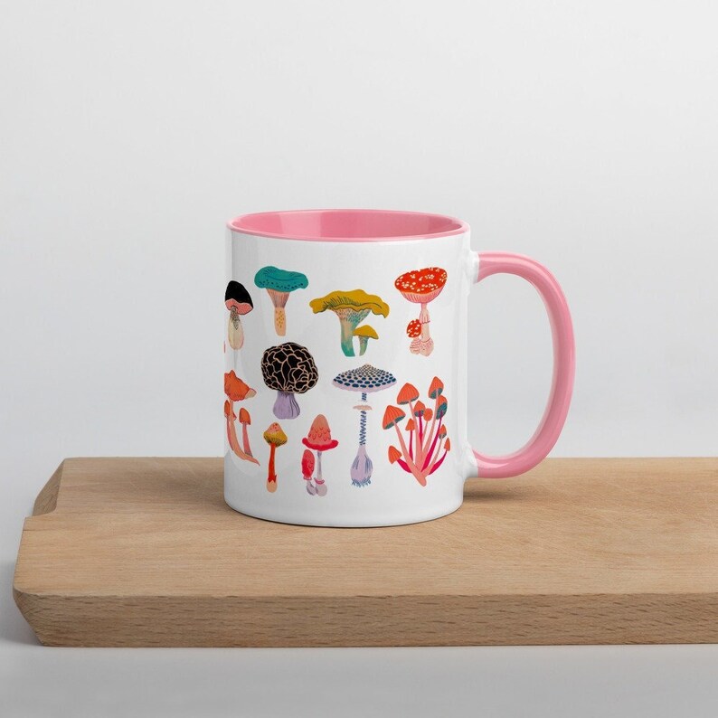 May include: White ceramic mug with a pink rim and handle. The mug features a colourful illustration of various mushrooms.