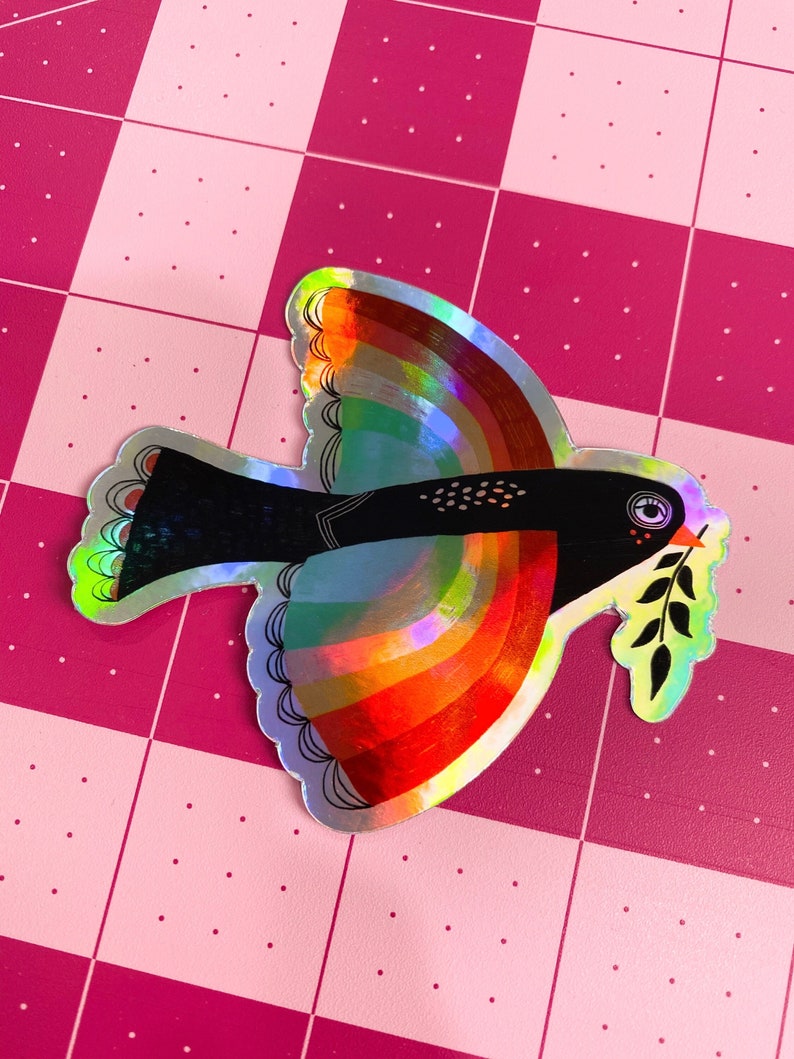 May include: A holographic sticker of a black and white bird with a rainbow wingspan and a green olive branch in its beak.