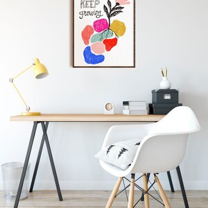 May include: A framed print with a colorful abstract design of a flower growing from a cluster of colorful shapes. The text "KEEP growing" is written in black on the print.