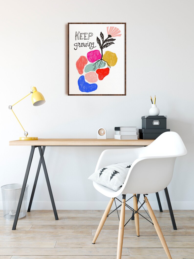 May include: A framed print with a colorful abstract design of a flower growing from a cluster of colorful shapes. The text "KEEP growing" is written in black on the print.