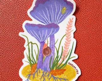 May include: A die-cut sticker featuring two purple mushrooms with visible gills, a small brown snail on a stalk, a tiny yellow beetle, green grass, and a pink plant sprig on a yellow patch of ground. The text DREAM FOLK is printed on the side.