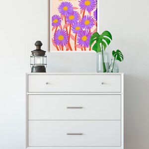 May include: A white framed print with a pink background and purple flowers. The text "You are not alone" is written in orange on the print.