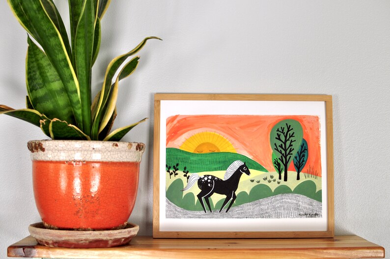 Puede incluir: Una ilustraci&oacute;n enmarcada de un caballo negro corriendo por un campo verde con un sol amarillo poni&eacute;ndose en el fondo. El sol tiene un ojo cerrado y el caballo tiene una crin y una cola blancas.