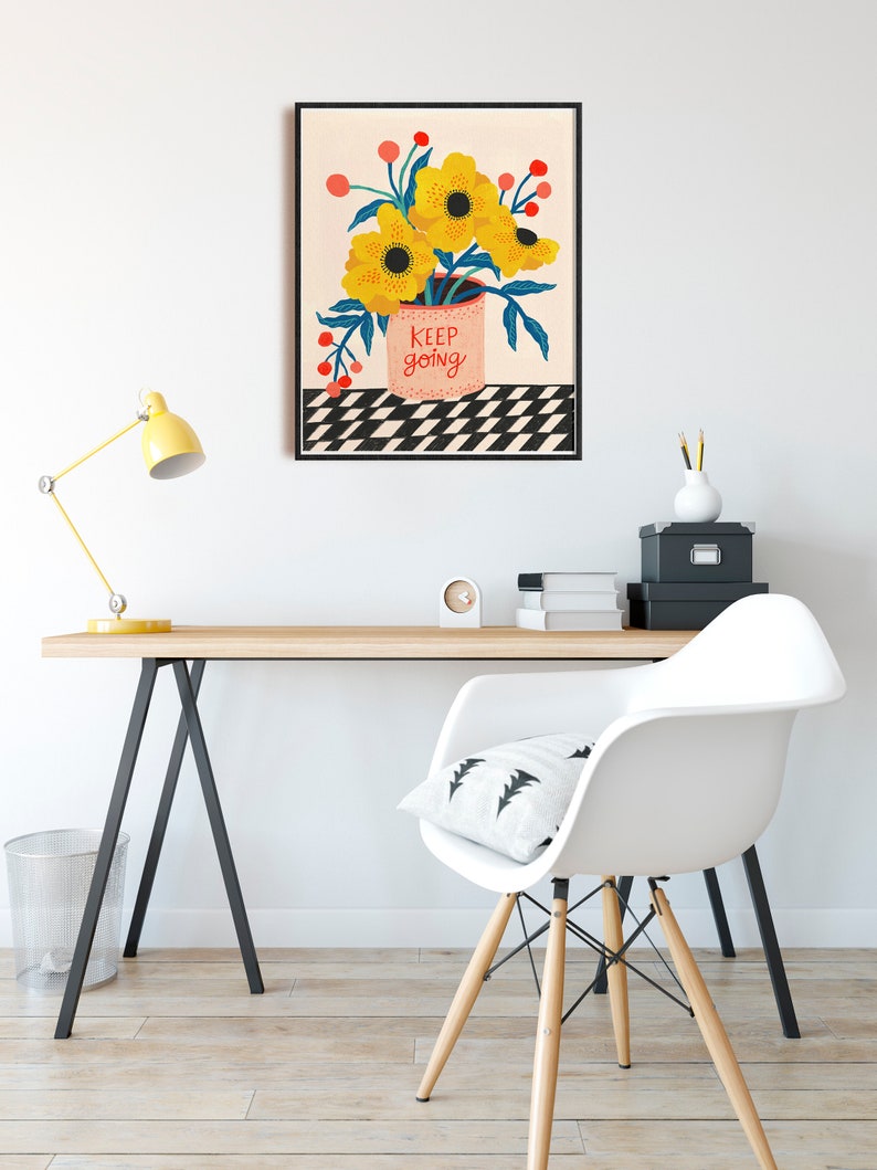 May include: A framed print with a black frame and a white background. The print features a bouquet of yellow flowers in a pink pot with the text "keep going" on the pot. The flowers are on a black and white checkered background.