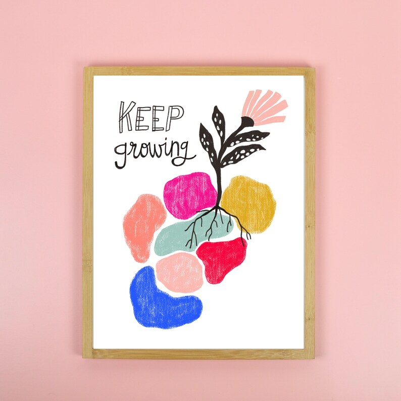 May include: A framed print with the text "KEEP growing" in black script. The print features a stylized black flower with roots growing into colorful abstract shapes.