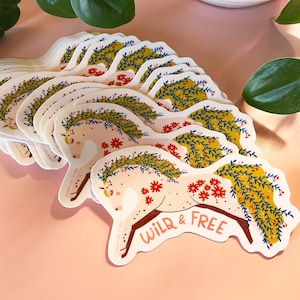 May include: A stack of white stickers with a colorful illustration of a horse with a floral wreath and the text "WILD & FREE".