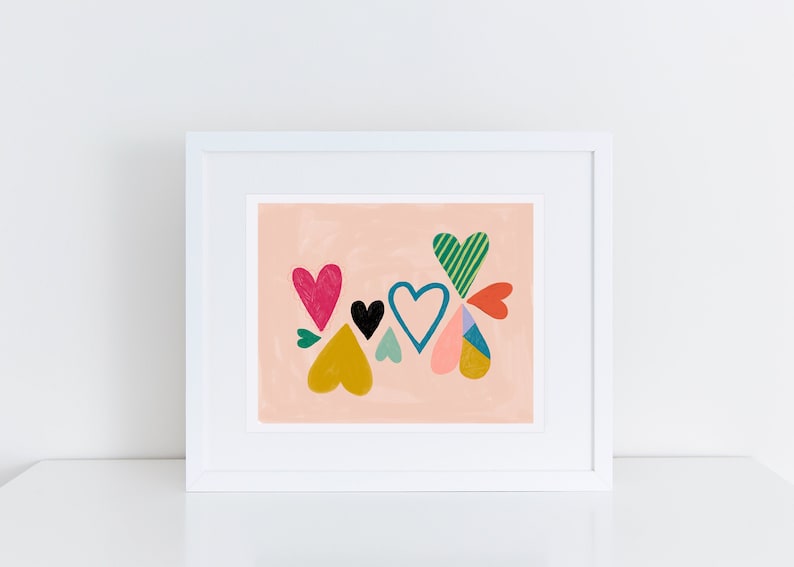 May include: A framed print with a pink background featuring a cluster of colorful hearts. The hearts are in various shapes and sizes, with patterns like stripes and polka dots.