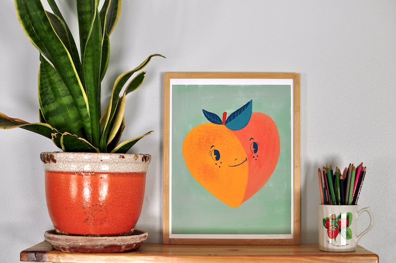 May include: A framed illustration of a peach with a smiling face. The peach is split in half, with one half a light orange color and the other half a darker orange color. The peach has a green stem and leaves. The background is a light blue-green color.