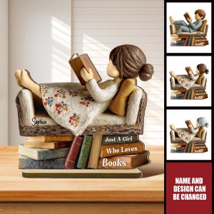 May include: A resin figurine of a person with brown hair in a bun, wearing a white dress with a floral pattern, reclining on a couch supported by a stack of books. The books feature the text "Just A Girl Who Loves Books" and the name "Sophia".