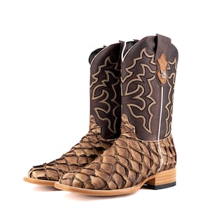 May include: A pair of brown cowboy boots featuring a scale-like pattern on the lower section and decorative stitching on the upper shaft. The boots have a square toe and a stacked heel, offering a distinctive Western style.