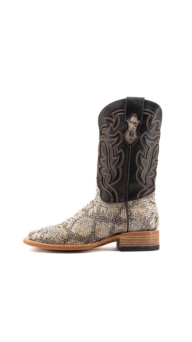May include: A tall cowboy boot with a snakeskin pattern on the foot and a black leather upper. The boot features decorative stitching and a square toe. The heel is approximately 1.5 inches high.