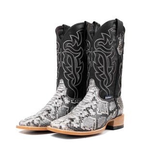 May include: A pair of cowboy boots with a snakeskin pattern on the foot and a black leather upper. The black upper features decorative stitching in a silver color. The boots have a square toe and a light brown sole.