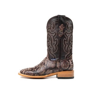 May include: A brown and tan cowboy boot with a snakeskin pattern on the lower portion and a decorative stitched design on the upper shaft. The boot has a square toe and a wooden heel. The brand name "Rockem" is visible.