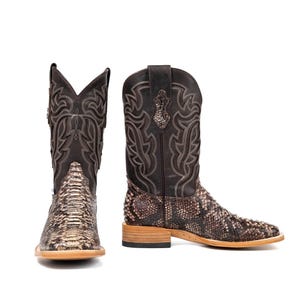 May include: Two brown and tan cowboy boots with a snakeskin pattern on the foot and a stitched design on the shaft. The boots have a square toe and a stacked heel, perfect for a Western-inspired look.