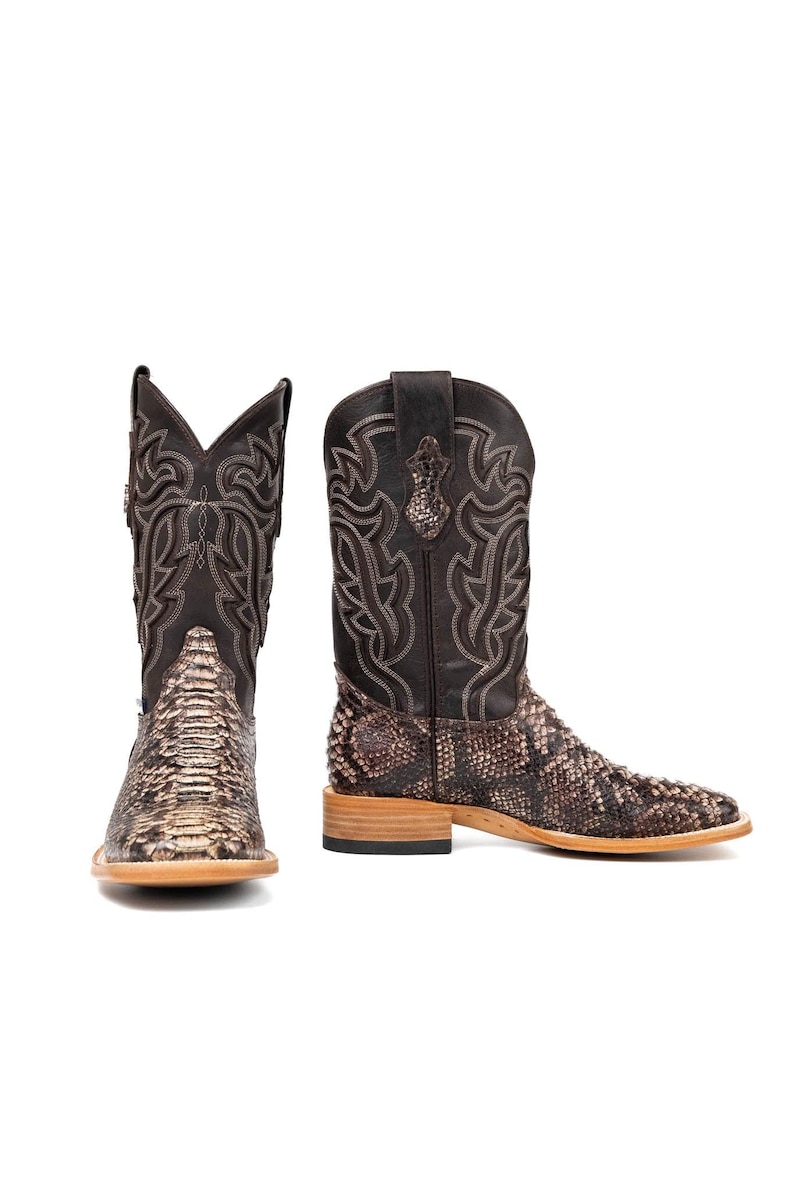 May include: Two brown and tan cowboy boots with a snakeskin pattern on the foot and a stitched design on the shaft. The boots have a square toe and a stacked heel, perfect for a Western-inspired look.