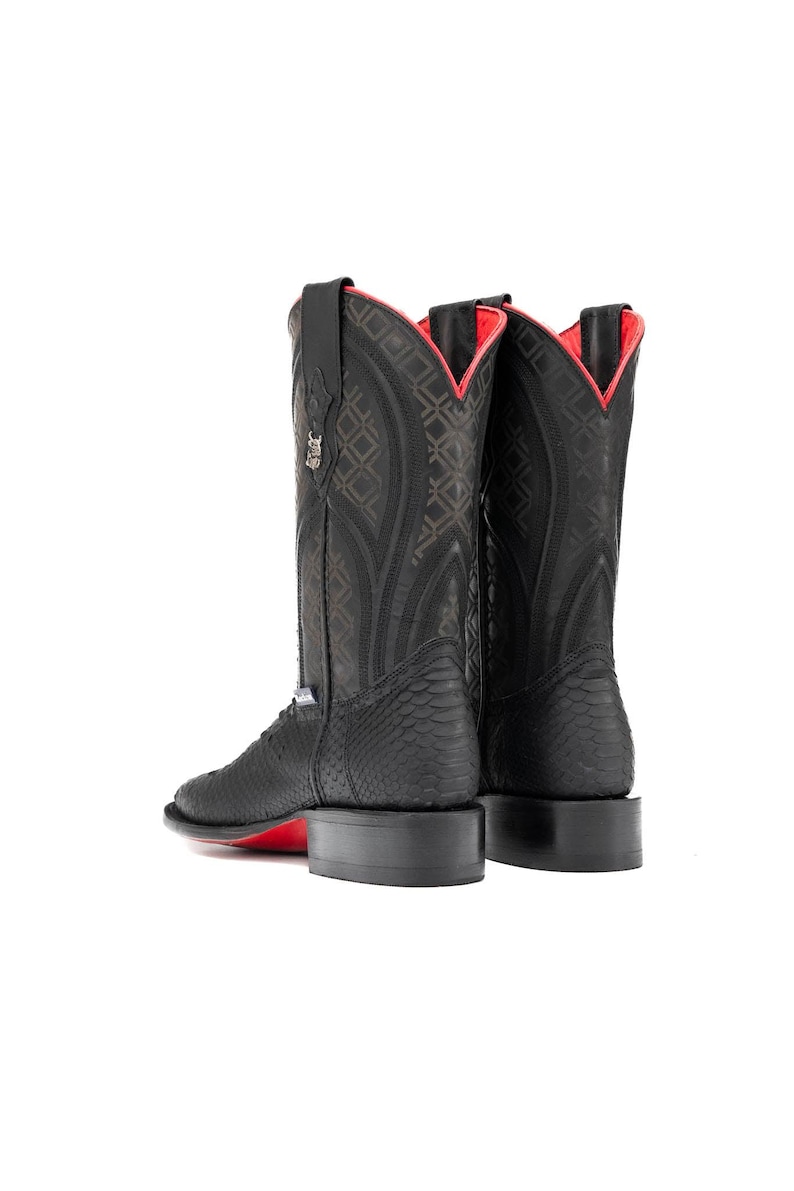 May include: Black cowboy boots with a textured pattern and red accents. The boots have a square toe and a red sole. The interior lining is red. The boots are set against a white background.