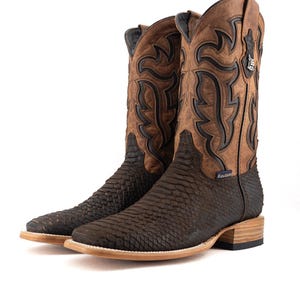Könnte beinhalten: Ein Paar braune Cowboy-Stiefel mit einem strukturierten, schlangenartigen Muster am unteren Teil und einem dekorativen Design am oberen Schaft. Die Stiefel haben eine quadratische Spitze und eine hellfarbige Sohle.