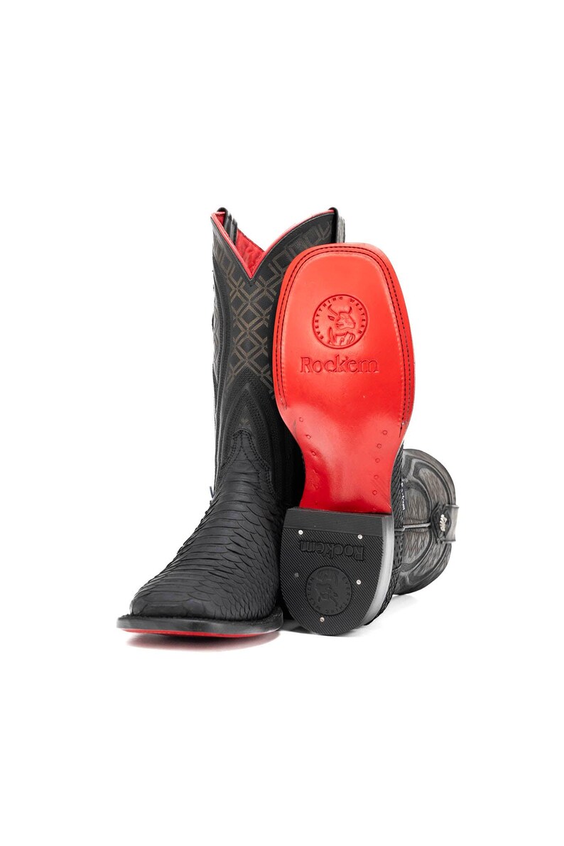 May include: Black cowboy boots with a textured pattern and red accents. The boots have a square toe and a red sole. The inside of the boot is red with a diamond pattern. The brand name "Rockem" is visible.