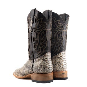 May include: A pair of cowboy boots with a snakeskin pattern on the lower part and a black leather upper. The boots have decorative stitching and a square toe. The soles are made of wood.