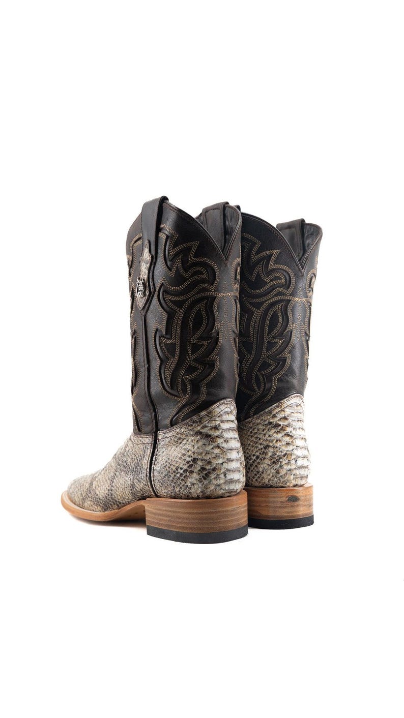 May include: A pair of cowboy boots with a snakeskin pattern on the lower part and a black leather upper. The boots have decorative stitching and a square toe. The soles are made of wood.