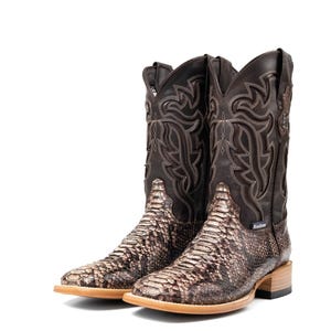 May include: A pair of brown and tan cowboy boots with a snakeskin pattern on the foot and a decorative stitched design on the upper shaft. The boots have a square toe and a stacked heel.