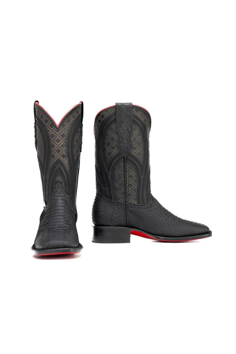 K&ouml;nnte beinhalten: Schwarze Cowboy-Stiefel mit strukturiertem Muster und roten Sohlen. Die Stiefel haben eine eckige Spitze und einen hohen Schaft mit dekorativen N&auml;hten. Die Innenausstattung ist rot. Diese Stiefel sind eine stilvolle Erg&auml;nzung f&uuml;r jede Garderobe.