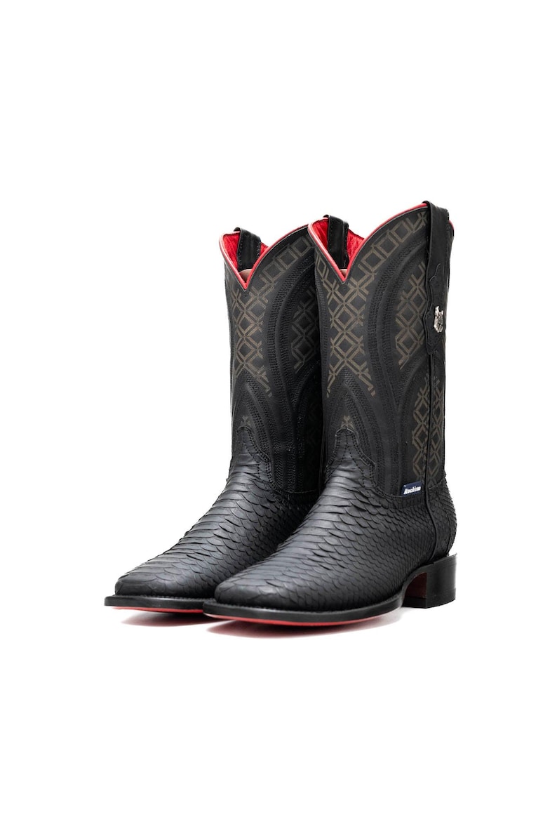 May include: A pair of black cowboy boots with a textured snakeskin pattern. The boots have a red interior and sole, with decorative stitching on the shaft. The heel is approximately 1.5 inches high.