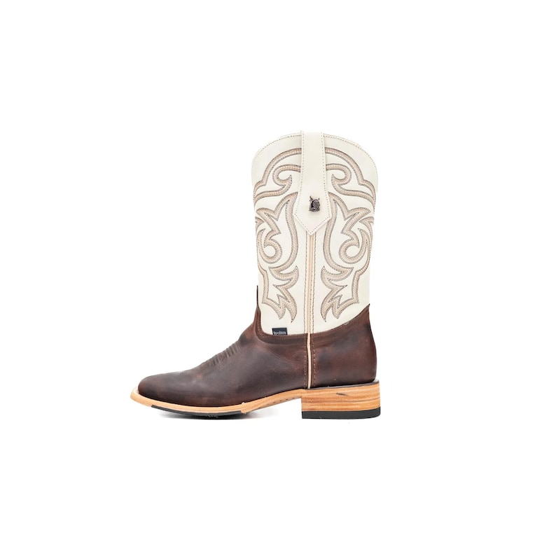 May include: A brown and cream cowboy boot with a square toe. The boot has a decorative stitched design on the cream upper shaft. The lower part of the boot is a darker brown, with a light-coloured sole and heel.