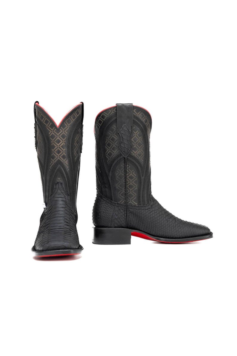 May include: Black cowboy boots with a textured pattern and red soles. The boots have a square toe and a tall shaft with decorative stitching. The interior trim is red. A stylish western boot.