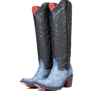 May include: A pair of tall cowboy boots. The boots have black leather uppers with decorative stitching and blue snakeskin-patterned vamps. The soles are red, and the heels are black.