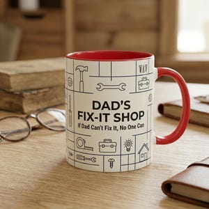 Puede incluir: Taza de cerámica blanca con interior y asa rojos. La taza presenta un diseño de contorno negro de herramientas y el texto "DAD'S FIX-IT SHOP If Dad Can't Fix It, No One Can."