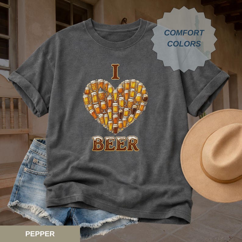 A pepper Comfort Colors tee featuring "I HEART BEER" text with a heart made of beer glasses. This Western Beer Shirt is a top-tier western graphics tee and wildwest shirt. For the beer realist, it’s the perfect alternative to a coors beer shirt, modelo beer shirt, or i love guinness tee. Great as a fermentation gift or groomsman gift. With an old school band tee vibe, it’s ideal for a gifted reader or when sometimes im hootin on a tripping shirt trip.