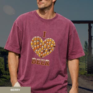 May include: Berry-coloured t-shirt featuring a heart made of beer mugs. The word "I" is above the heart, and the word "BEER" is below it. The shirt is a casual style.