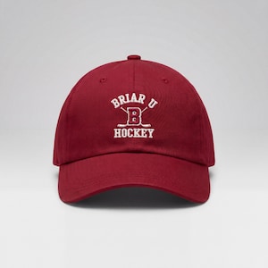 Może przedstawiać: Bordowa czapka bejsbolowa z białym haftem "Briar U Hockey". Czapka ma zakrzywiony daszek i regulowany pasek. Wykonana z miękkiej, trwałej tkaniny.