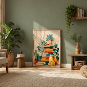May include: A framed art print depicts a stack of colorful books with potted plants and a yellow cat. The artwork is displayed in a room with a large plant, a wooden side table, and a beige rug.
