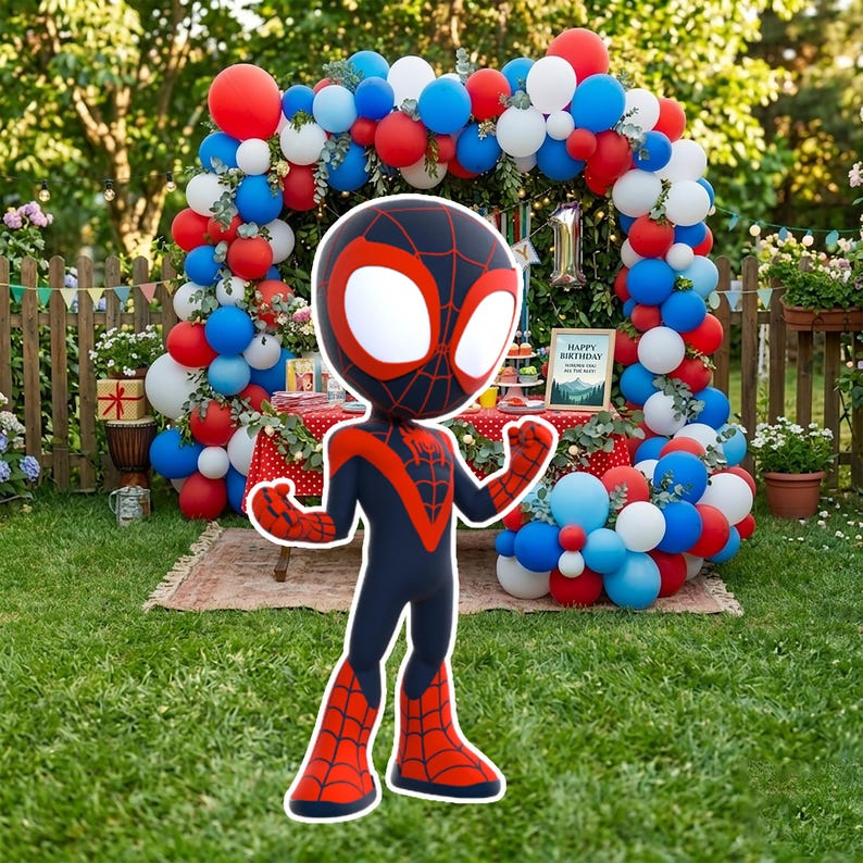 May include: A large, cartoon-style figure of a superhero in a black and red suit, with large white eyes. The figure is in a grassy yard, with a balloon arch in the background. The arch is decorated with red, white, and blue balloons, and a table with a red and white polka dot tablecloth.