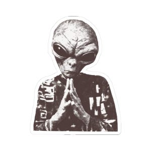 May include: A sticker featuring a sepia-toned illustration of an alien with large black eyes and clasped hands. The alien is wearing a patterned shirt. The sticker has a white border.