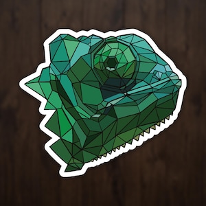 May include: A geometric illustration of a chameleon's head in shades of green. The design uses a low-poly style, with each facet of the chameleon's head and eye defined by sharp, angular lines. The artwork is set against a dark wood grain background.